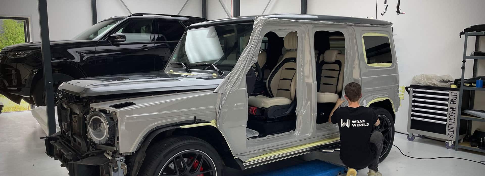 A De Wrap Wereld specialist applies wrap film to a Mercedes G-Class